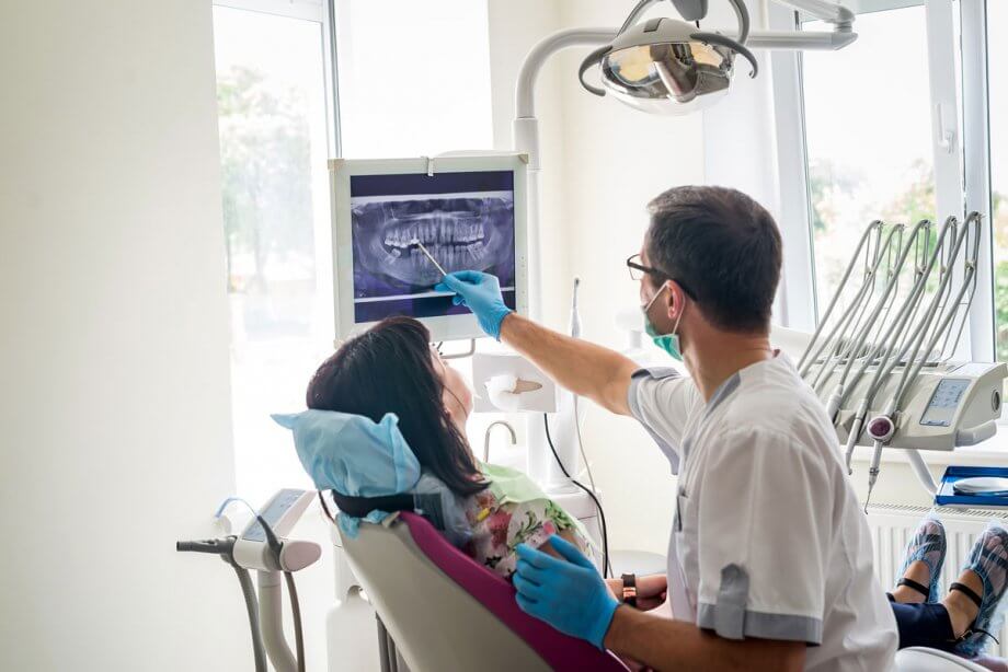 endodontist pointing out digital X-ray to patient in dental chair