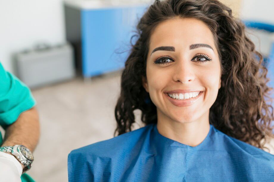 woman with curly hair smiles from dental chair